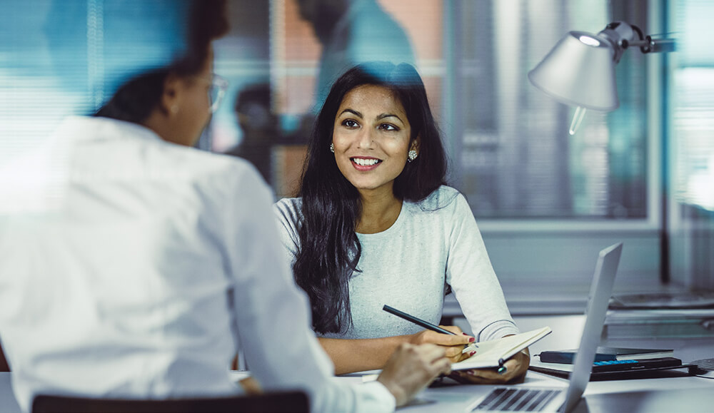 woman in corporate setting sitting with an employee