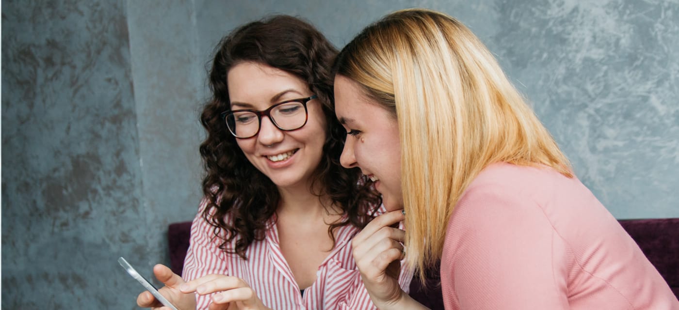 two women looking at a phone and smiling