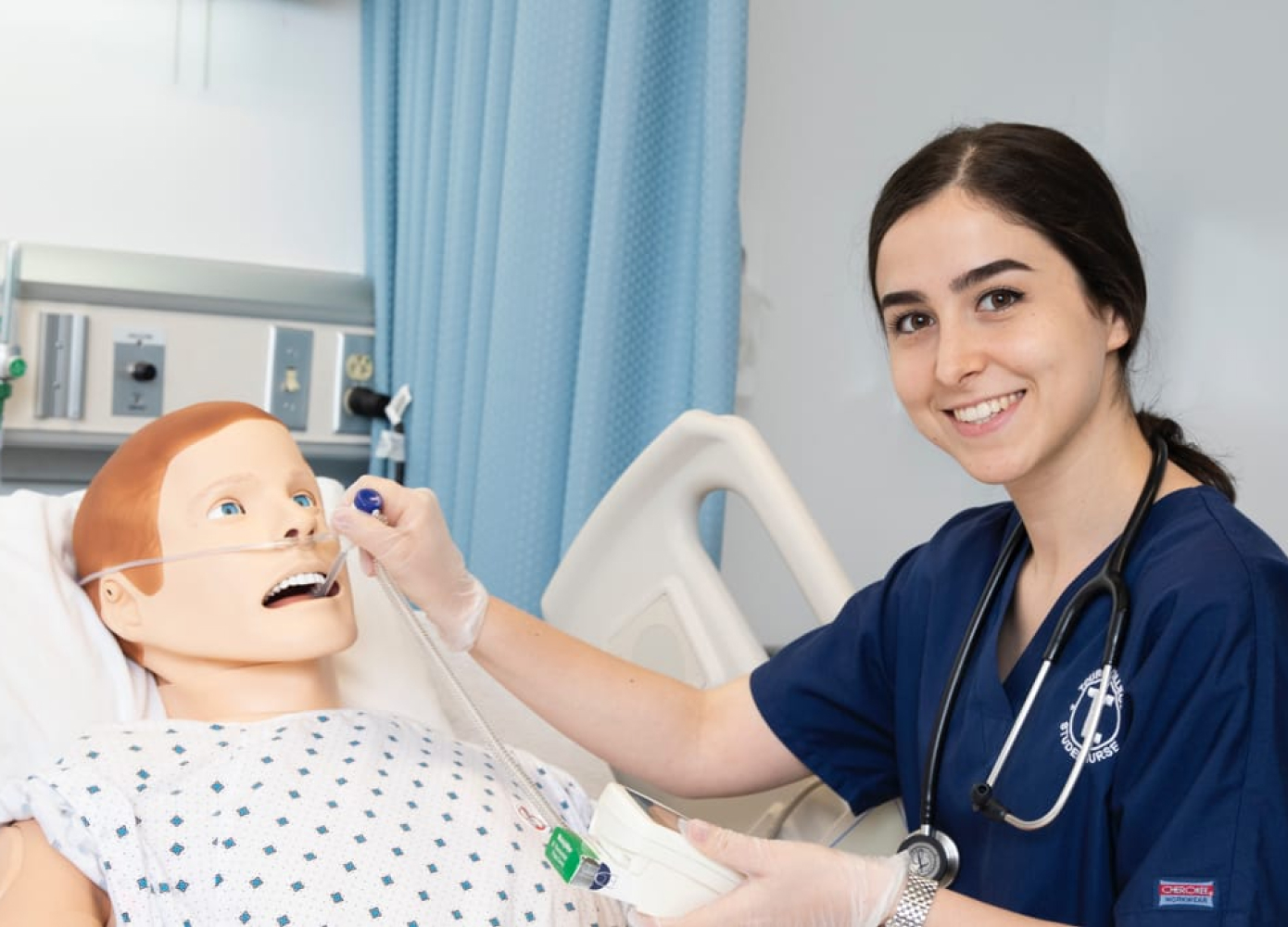Nursing student smiling while learning using medical manikin in lab