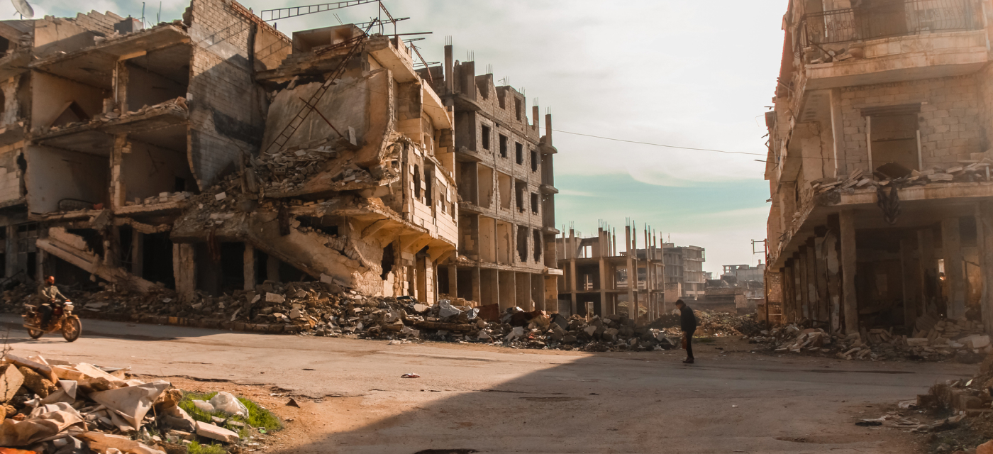 Person walking next to destroyed buildings in Aleppo, Syria