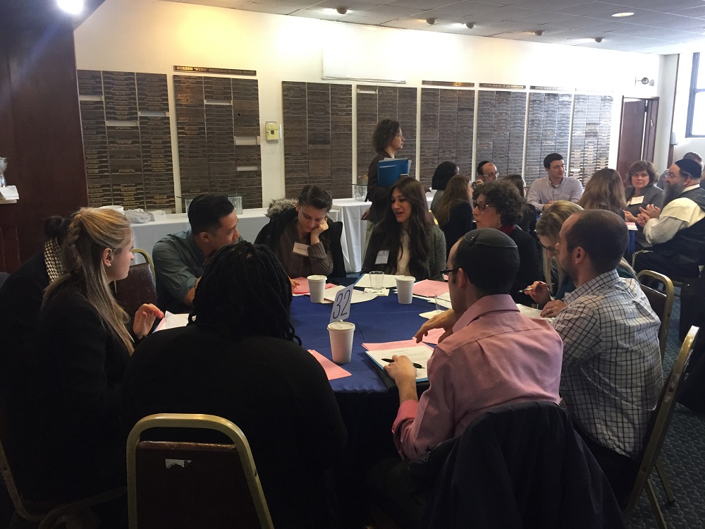 students sitting around tables in a synagogue gathering room.