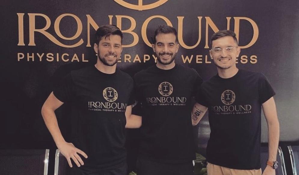 Three physical therapists standing by a sign for their clinic, which reads Ironbound Physical Therapy and Wellness