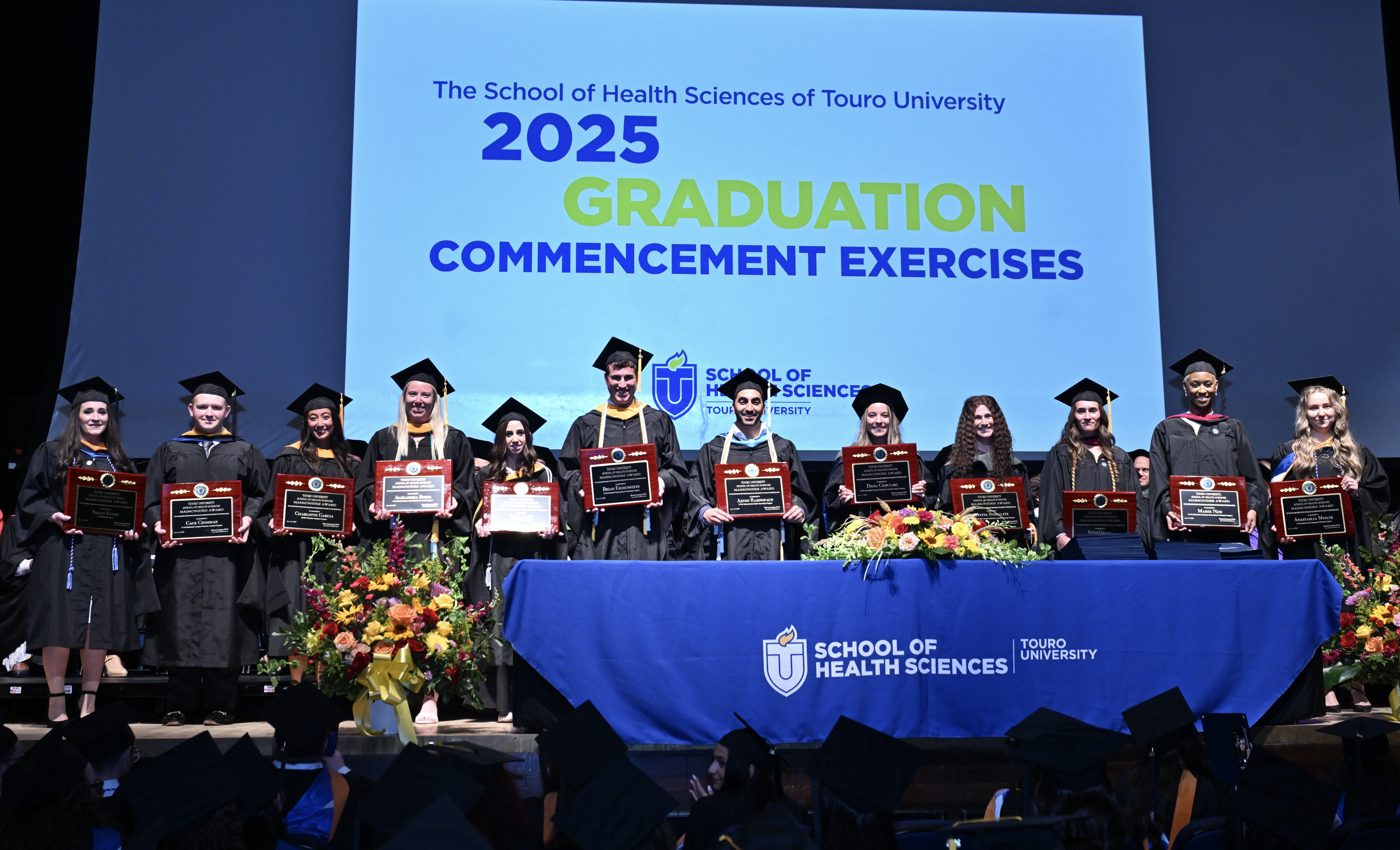 Touro School of Health Sciences graduates and Maimonides Award winners stand on the stage.